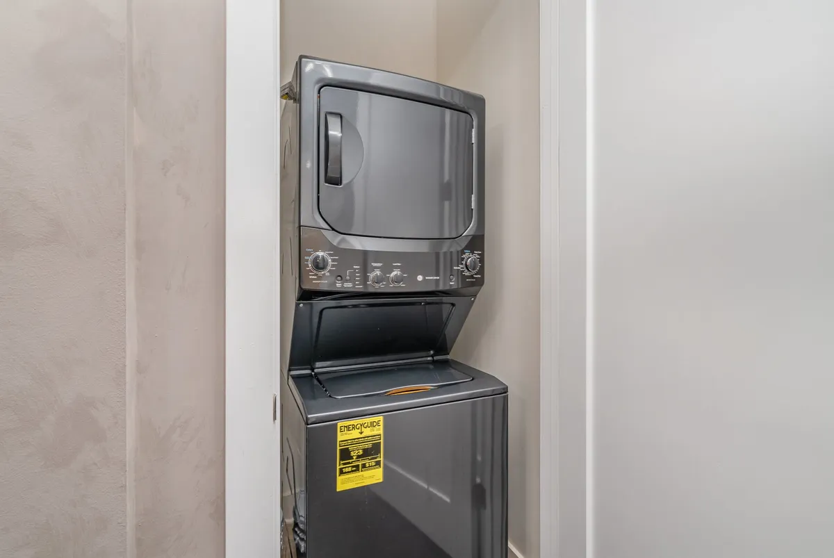 A stacked washer and dryer unit in a dedicated laundry area, demonstrating practical amenities for everyday living. The setting is clean and functional, emphasizing convenience for residents.