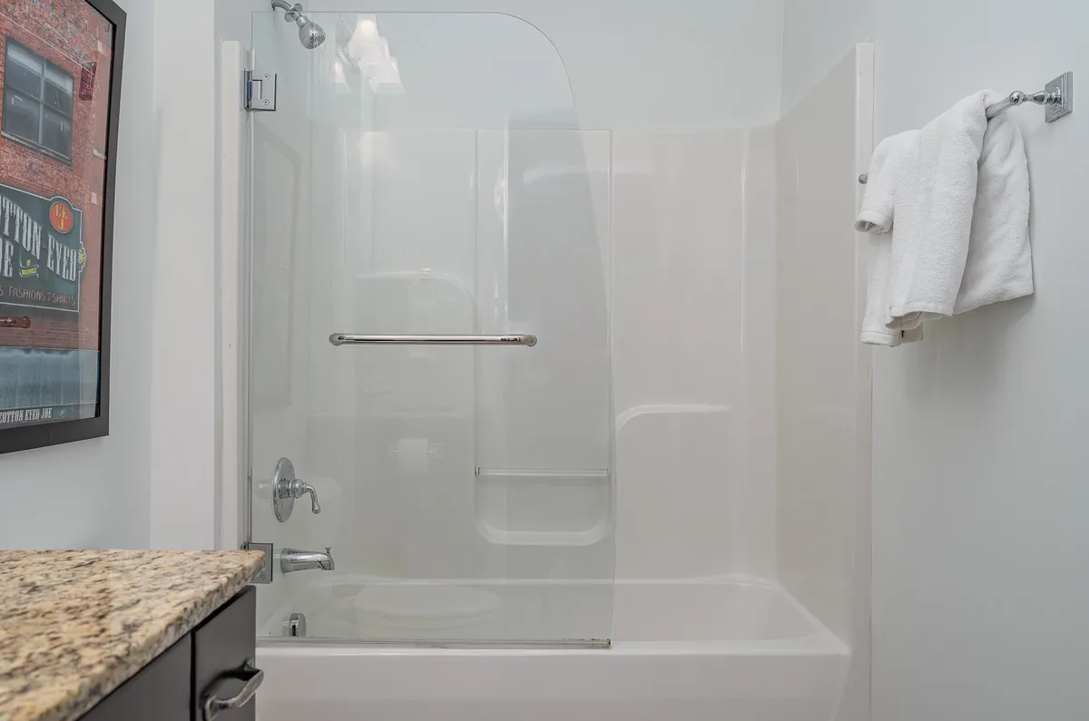A fresh and inviting bathroom showcasing a glass shower enclosure, granite countertop, and neatly hung towels on a rack. The lighting is bright and natural, and the space feels clean and welcoming. The setup suggests both functionality and comfort, making it ideal for post-adventure relaxation or a quick morning routine.