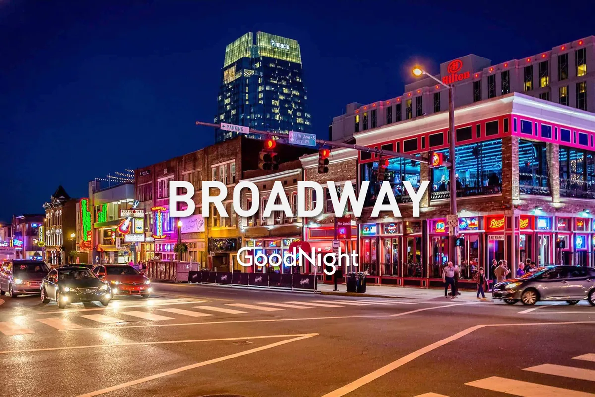 A vibrant Nashville street scene at night featuring neon signs, bustling sidewalks, and people enjoying the urban nightlife. The illuminated buildings and visible signage evoke the energy of Broadway and the city's iconic honky-tonks.