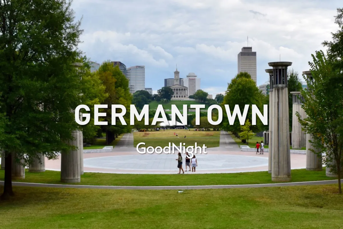 The image shows a peaceful green park area with trees, walking paths, and a clear view of the city skyline in the background. People can be seen walking and socializing, creating a sense of community and relaxation within an urban setting.
